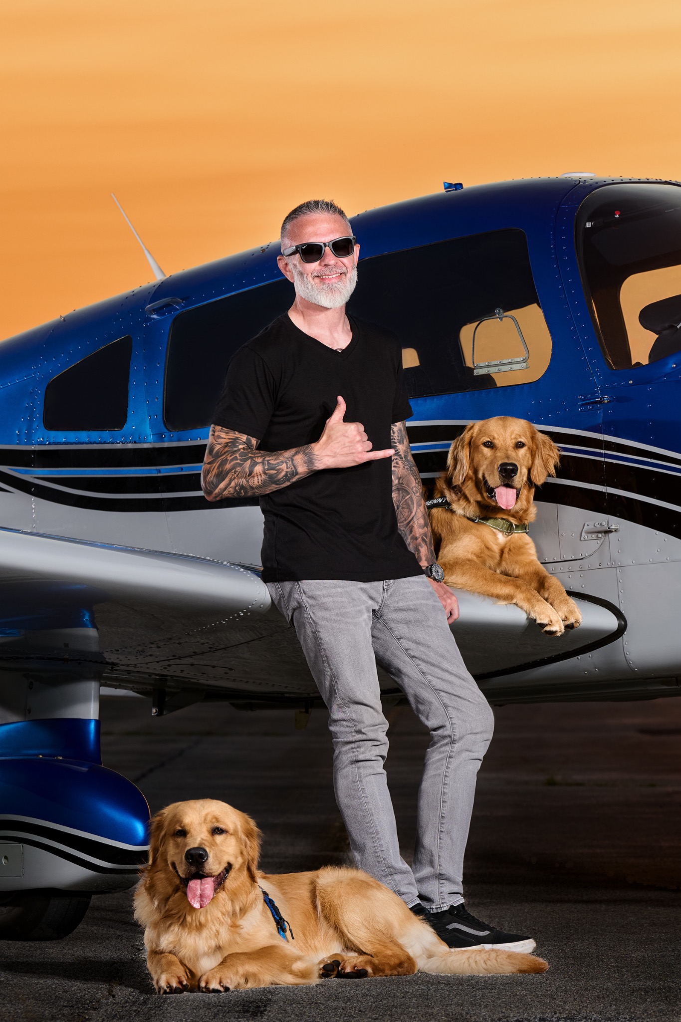 Ed Foley, Marshall and Benny beside a blue airplane at sunset